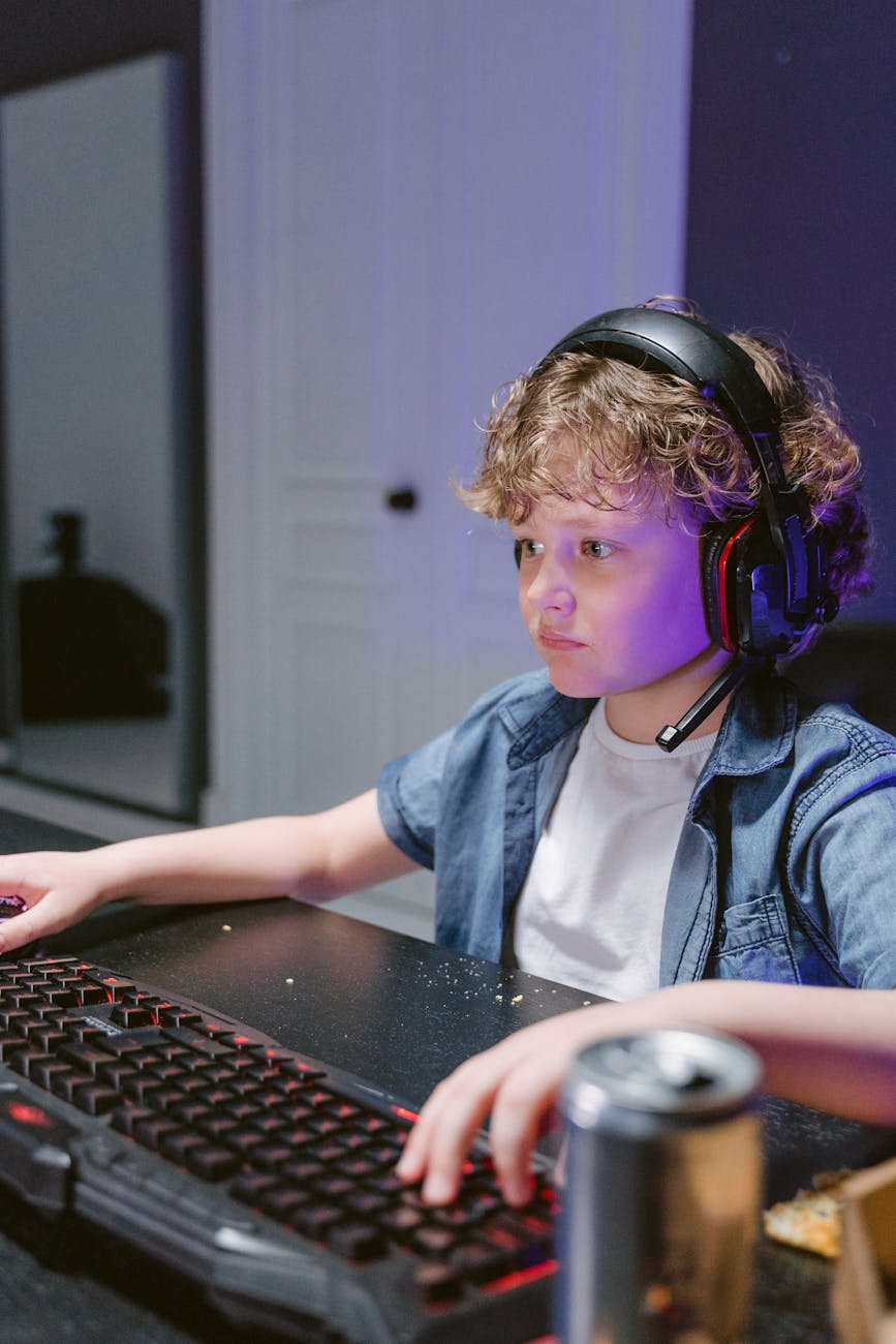 a boy wearing headset while busy typing on his keyboard